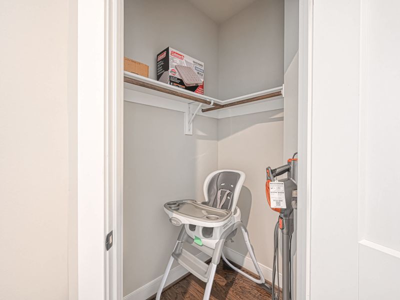 Small storage closet with essential items including a high chair and cleaning supplies