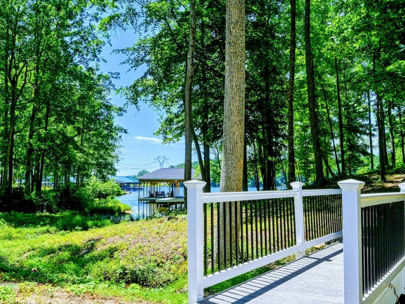A charming bridge leading through lush woods to a peaceful lakefront dock.