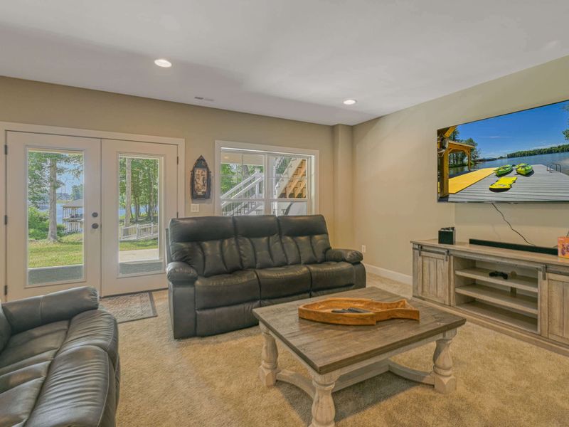 Comfortable living area with leather sofas, a large TV, and direct access to outdoor views and activities.