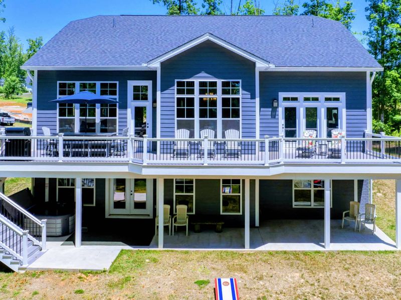 Spacious two-story lakefront home with multiple outdoor seating areas and a hot tub.