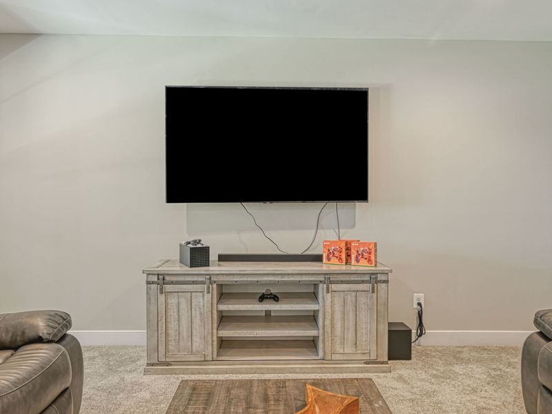 Entertainment area with a large TV, gaming console, and cozy seating for your relaxation.