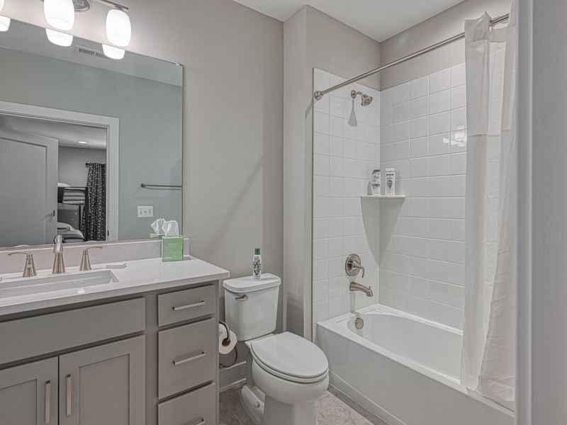 Clean and modern bathroom with a vanity, toilet, and bathtub-shower combo