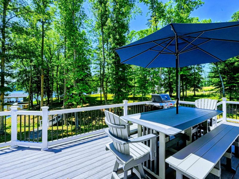Spacious outdoor dining area with a BBQ grill and umbrella, perfect for enjoying meals surrounded by nature.