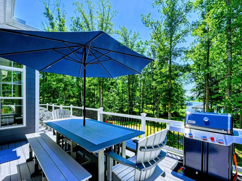 Spacious outdoor dining area with a BBQ grill and umbrella, perfect for enjoying meals surrounded by nature.