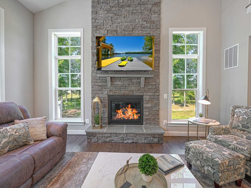 Relax in a cozy living room featuring a stone fireplace and large windows with serene views.