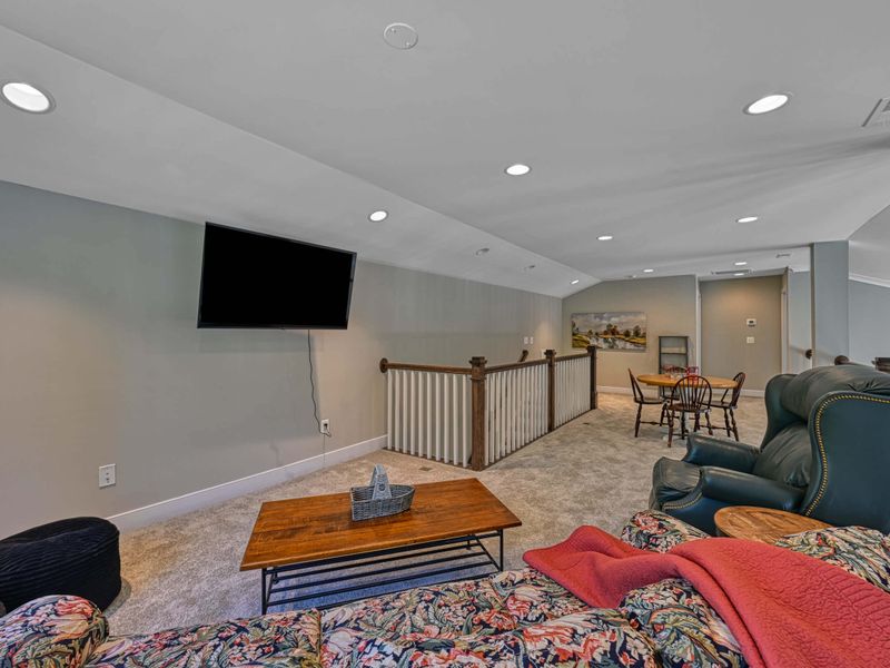 Cozy loft area with a TV, comfortable seating, and a small game table