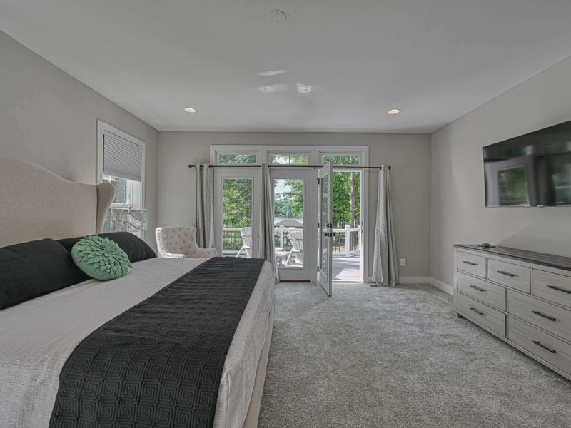 Spacious Primary Bedroom with a king-size bed, TV, and direct access to a private deck