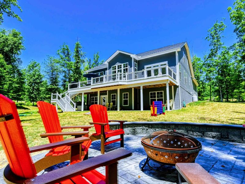 Charming lakeside retreat with a spacious deck, vibrant red Adirondack chairs, and a cozy fire pit