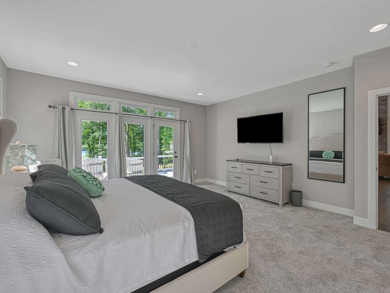 Elegant Primary Bedroom with a king-size bed, TV, and direct access to a private deck with garden views