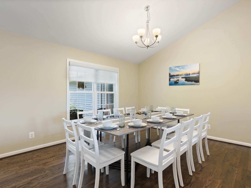 A bright and spacious dining area with a large table set for gatherings, seamlessly flowing into the open-concept living room for a welcoming and social atmosphere.