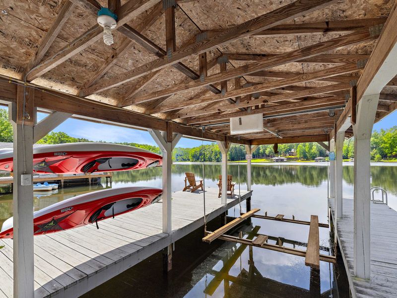 A covered dock featuring a spacious boat slip and scenic lake views, providing the perfect setup for boating enthusiasts and lakeside relaxation. (boat lift not for guest use)