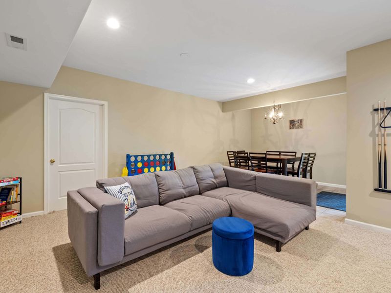 A spacious game room featuring a pool table, cozy seating, and rustic sliding barn doors leading to a home theater, perfect for entertainment and relaxation.