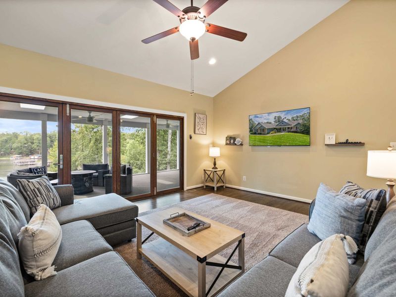 An inviting open-concept living space with a cozy sectional sofa, high ceilings, and a modern kitchen, perfect for gathering and relaxation.