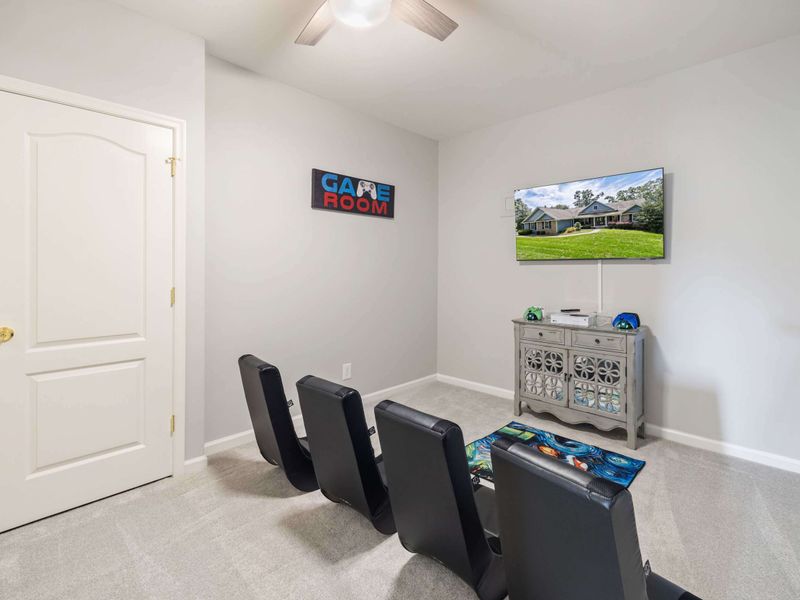 A cozy gaming room with comfortable seating, a TV, and playful decor, creating the perfect space for video games or movie time.