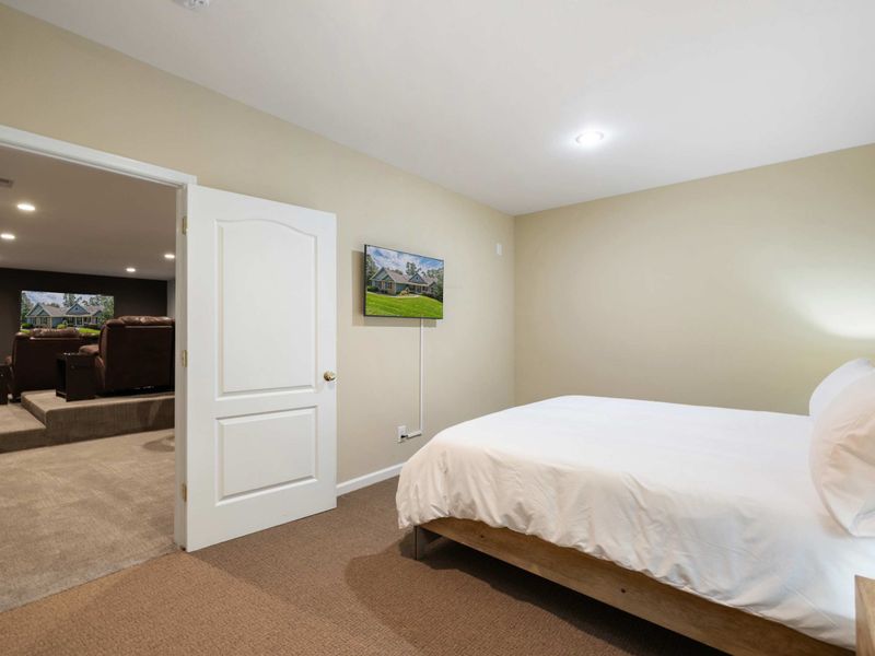 A cozy bedroom with a minimalist design, located conveniently next to the home theater for easy access to entertainment.