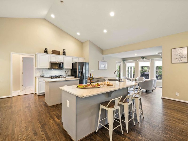 A spacious and modern kitchen with a large marble island, plenty of seating, and an open layout connected to the dining area, perfect for entertaining and family meals.