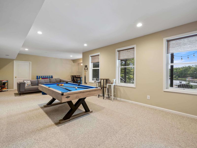 A spacious game room featuring a pool table, cozy seating, and rustic sliding barn doors leading to a home theater, perfect for entertainment and relaxation.