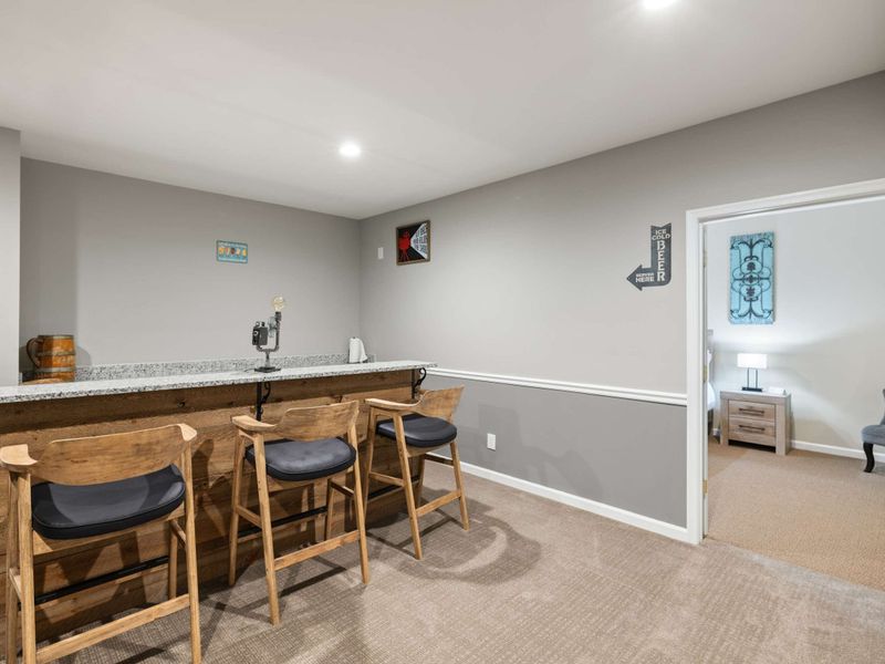 A cozy home theater with tiered seating, plush recliners, and a convenient bar area, perfect for movie nights and entertaining guests.
