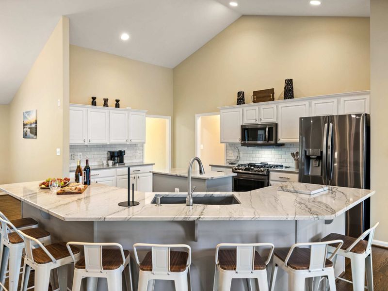 A spacious and modern kitchen with a large marble island, plenty of seating, and an open layout connected to the dining area, perfect for entertaining and family meals.
