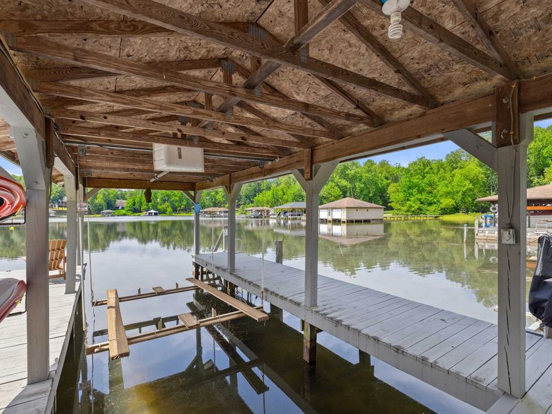A covered dock featuring a spacious boat slip and scenic lake views, providing the perfect setup for boating enthusiasts and lakeside relaxation. (boat lift not for guest use)