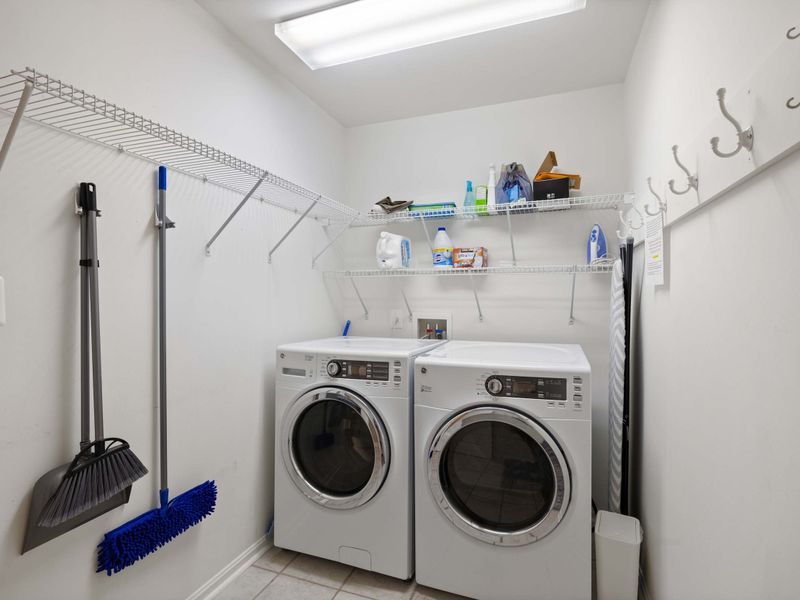 A fully equipped laundry room with modern appliances, ample shelving, and convenient hooks for storage and organization.