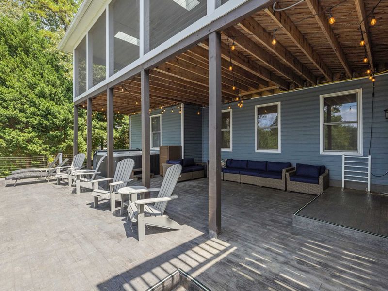 A spacious deck with Adirondack chairs overlooking a beautifully landscaped yard and a tranquil lake, perfect for relaxing and taking in the view.