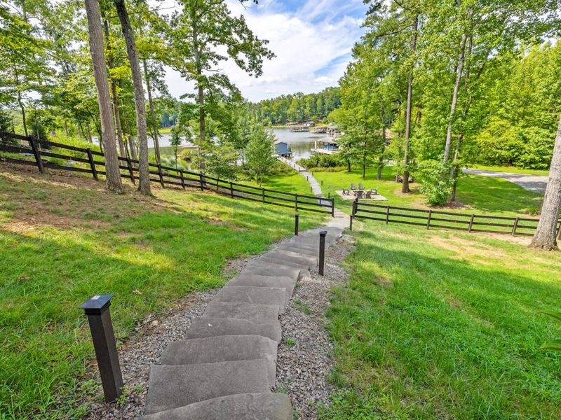 A picturesque lakefront property featuring a serene dock, lush greenery, and a cozy fire pit, perfect for relaxation and outdoor enjoyment.