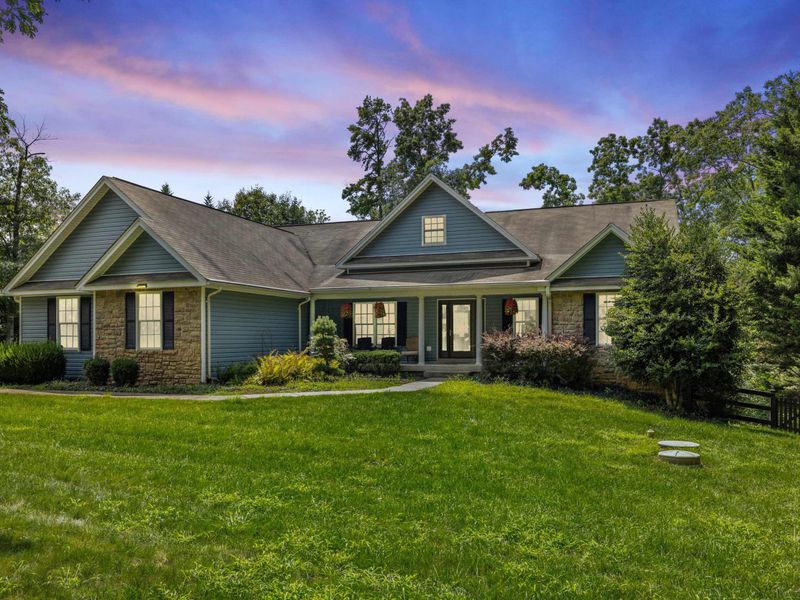 A charming and spacious home with a well-maintained lawn, inviting front porch, and picturesque surroundings, perfect for a relaxing stay.