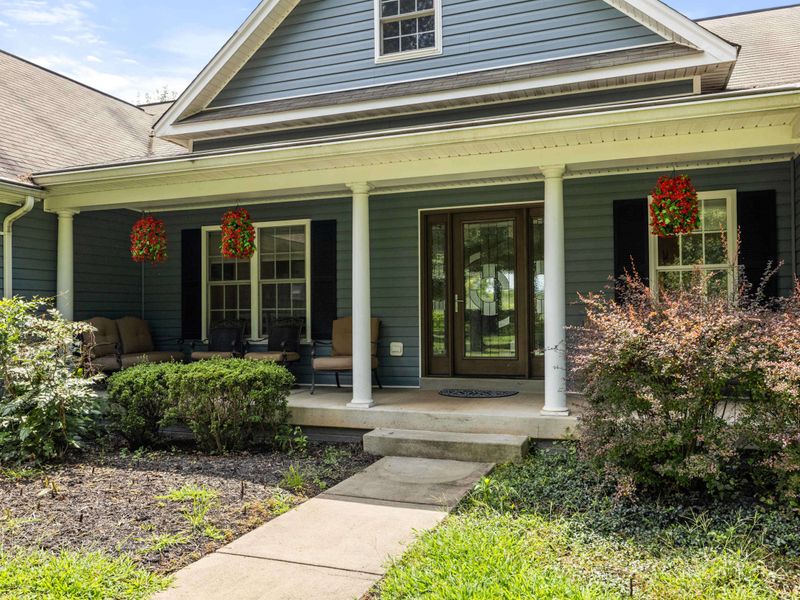 A charming and spacious home with a well-maintained lawn, inviting front porch, and picturesque surroundings, perfect for a relaxing stay.