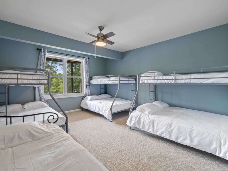 A spacious bunk room with multiple beds and a calming blue color scheme, ideal for accommodating groups or families.