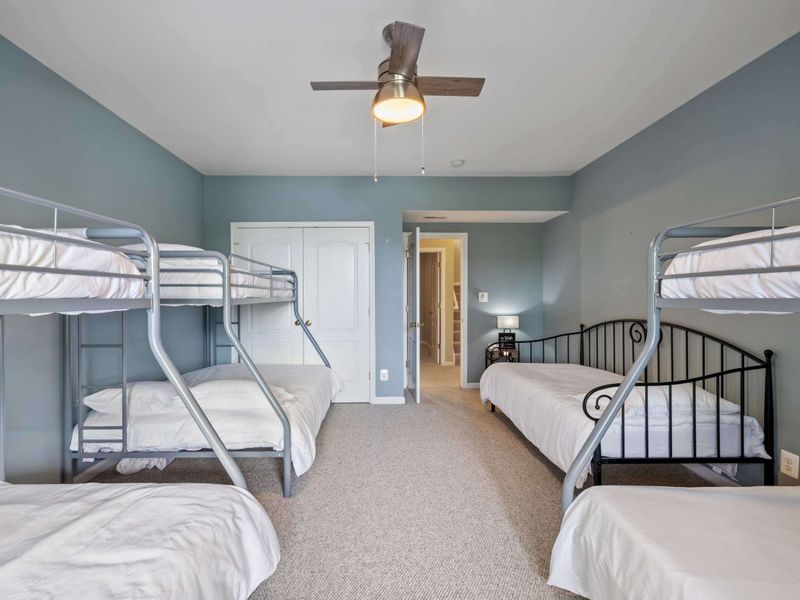 A spacious bunk room with multiple beds and a calming blue color scheme, ideal for accommodating groups or families.