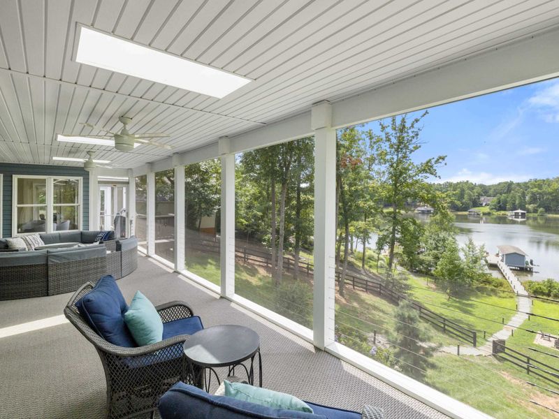 A spacious screened-in porch with cozy seating and stunning views of the lake, perfect for relaxing or entertaining in comfort.