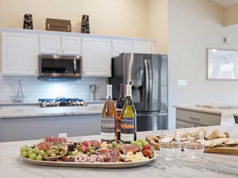 Kitchen - Charcuterie board and local Virginia wines staged on the marble island with the gourmet kitchen behind.
