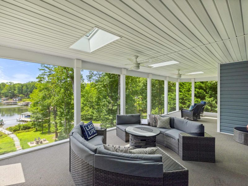 A spacious screened-in porch with cozy seating and stunning views of the lake, perfect for relaxing or entertaining in comfort.