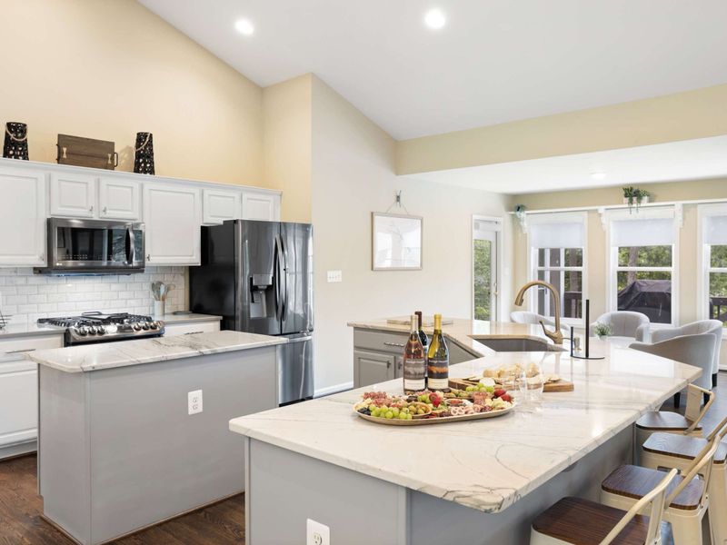 A spacious and modern kitchen with a large marble island, plenty of seating, and an open layout connected to the dining area, perfect for entertaining and family meals.