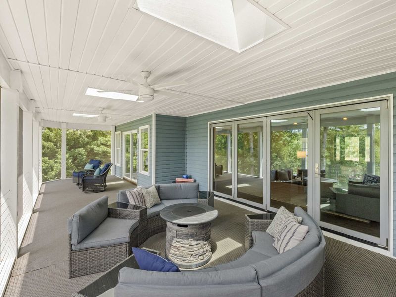 A spacious screened-in porch with cozy seating and stunning views of the lake, perfect for relaxing or entertaining in comfort.