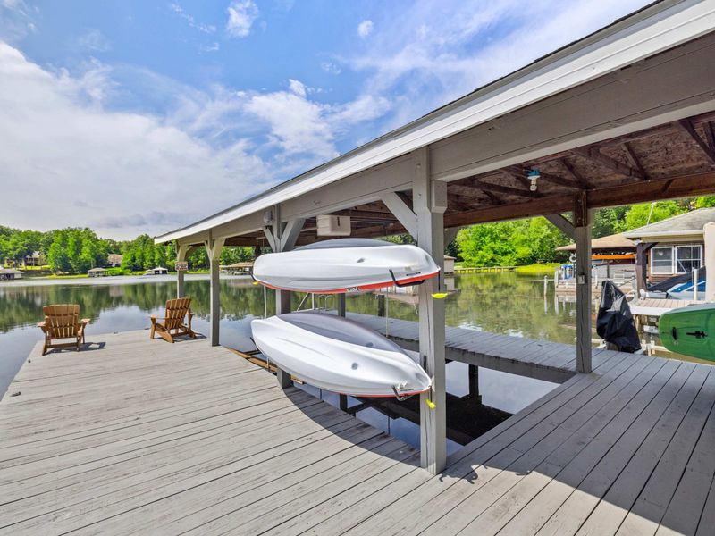 A covered dock featuring a spacious boat slip and scenic lake views, providing the perfect setup for boating enthusiasts and lakeside relaxation.