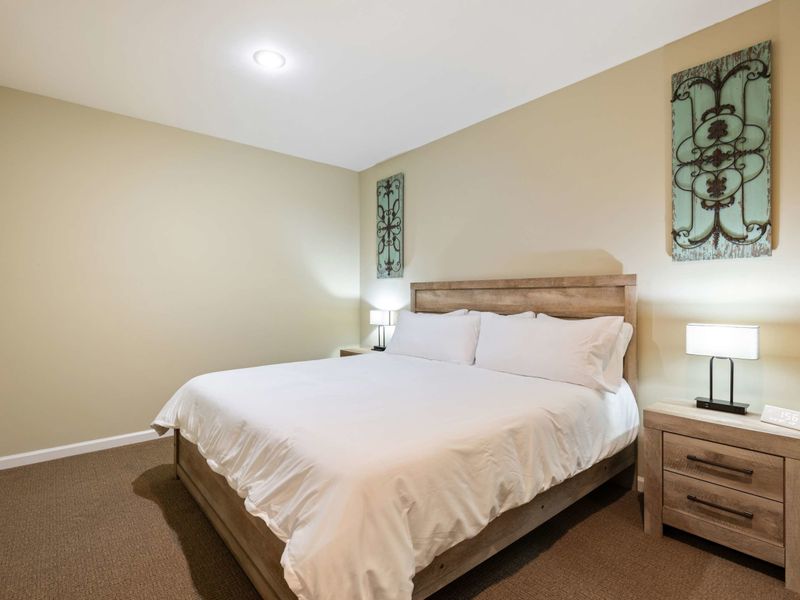 A cozy bedroom with a minimalist design, located conveniently next to the home theater for easy access to entertainment.