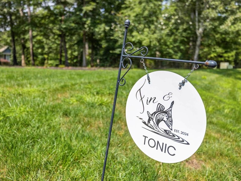 A charming custom sign reading "Fin & Tonic," set against a lush green backdrop, adding a personalized and inviting touch to the property.