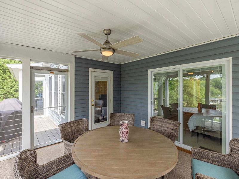 A charming screened-in porch with a ceiling fan and a cozy dining area, offering a comfortable space to enjoy meals with a view.