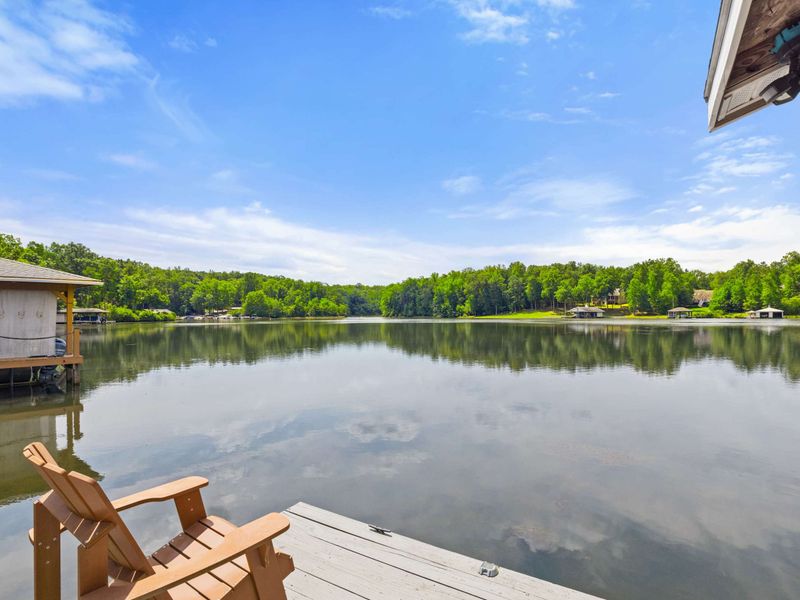 A serene lakeside view from a dock equipped with Adirondack chairs, perfect for enjoying peaceful moments by the water.