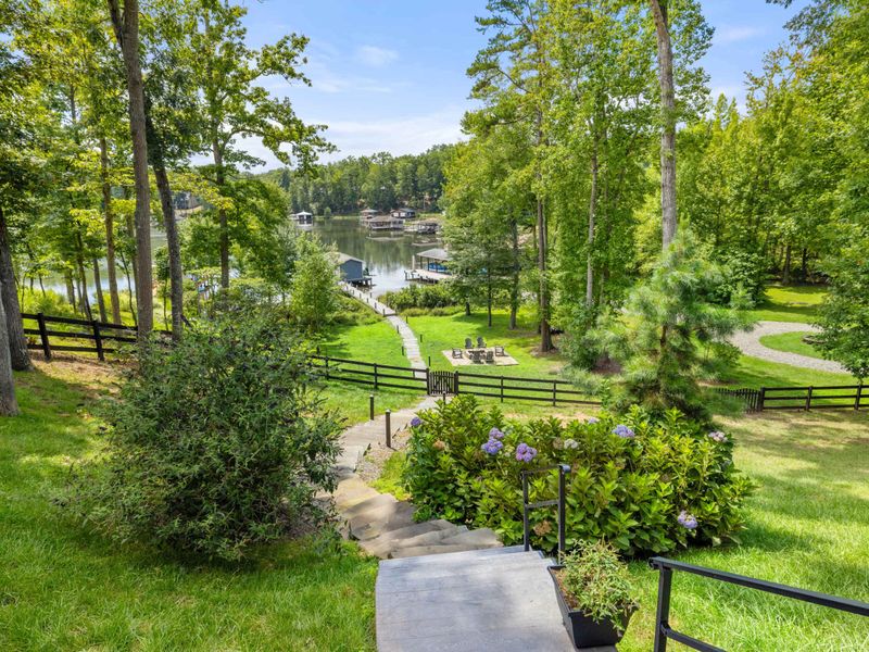 A picturesque lakefront property featuring a serene dock, lush greenery, and a cozy fire pit, perfect for relaxation and outdoor enjoyment.