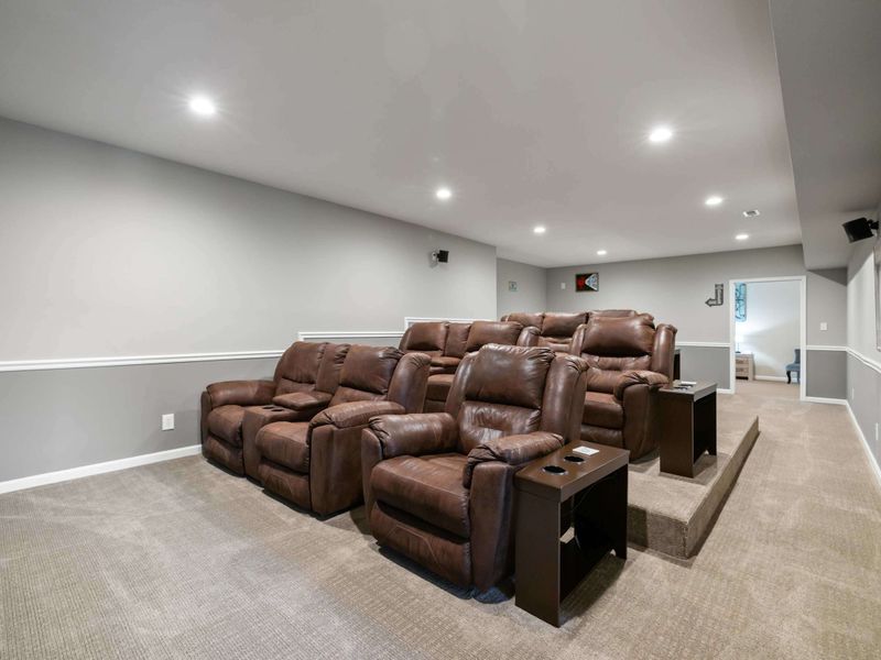 A cozy home theater with tiered seating, plush recliners, and a convenient bar area, perfect for movie nights and entertaining guests.