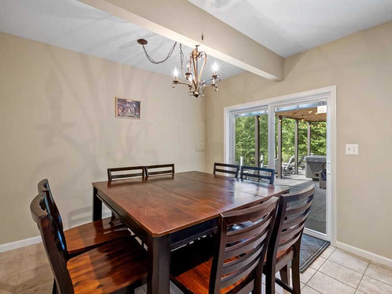 A welcoming dining area with a wooden table, adjacent to a game room and a covered patio, offering versatile spaces for dining and entertainment.