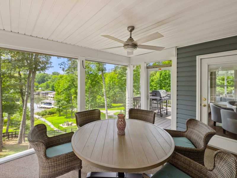 A charming screened-in porch with a ceiling fan and a cozy dining area, offering a comfortable space to enjoy meals with a view.