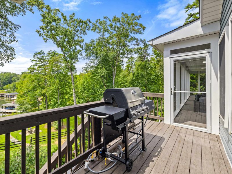 A cozy deck with a grill overlooking a serene lake, perfect for outdoor cooking and enjoying the beautiful surroundings.