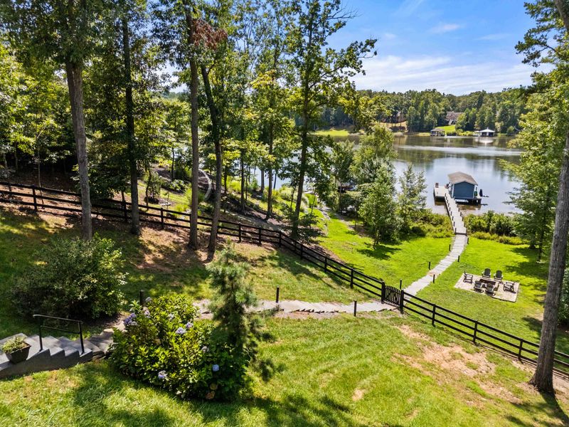 A picturesque lakefront property featuring a serene dock, lush greenery, and a cozy fire pit, perfect for relaxation and outdoor enjoyment.