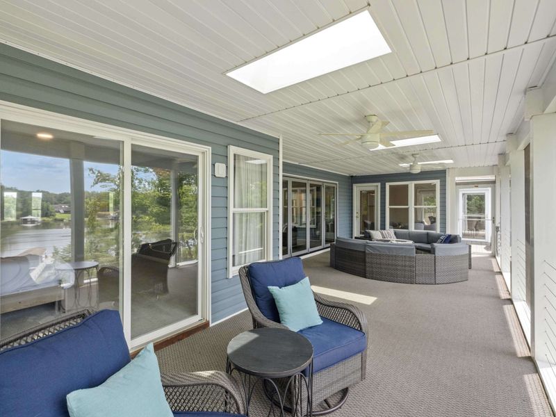 A spacious screened-in porch with cozy seating and stunning views of the lake, perfect for relaxing or entertaining in comfort.