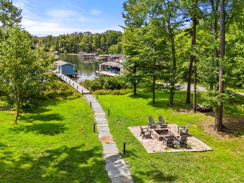 A picturesque lakefront property featuring a serene dock, lush greenery, and a cozy fire pit, perfect for relaxation and outdoor enjoyment.