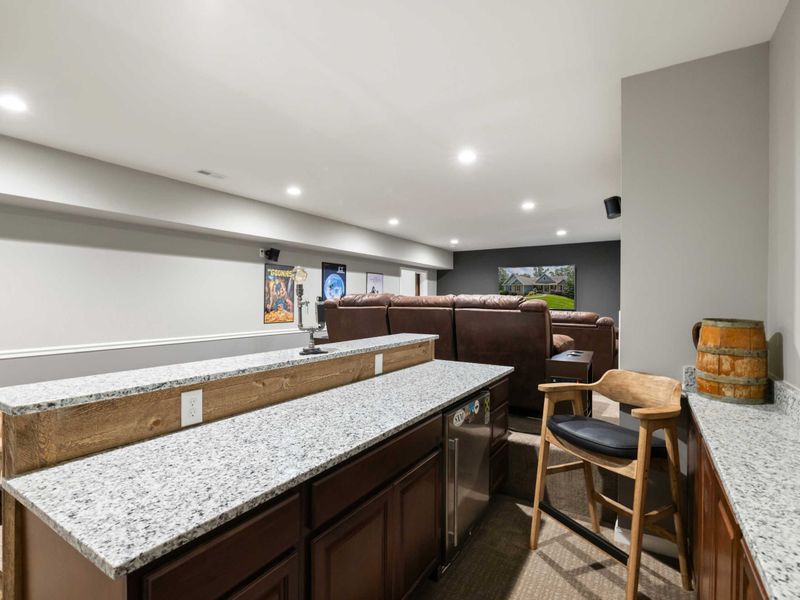 A cozy home theater with tiered seating, plush recliners, and a convenient bar area, perfect for movie nights and entertaining guests.